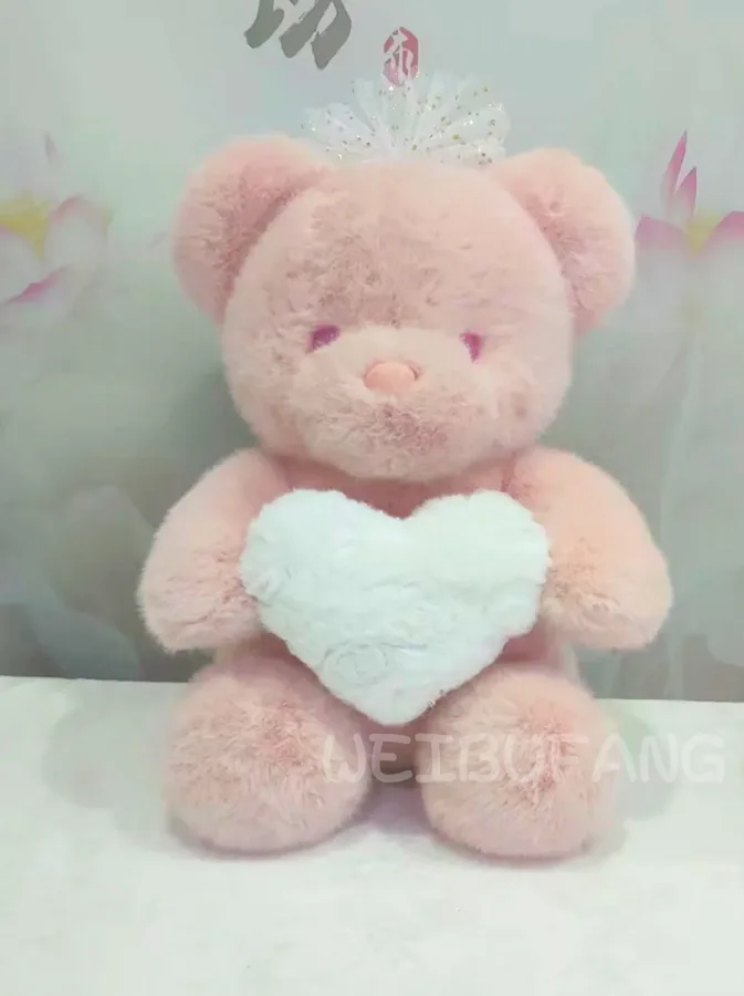 A pink teddy bear holding a soft mint-coloured heart.