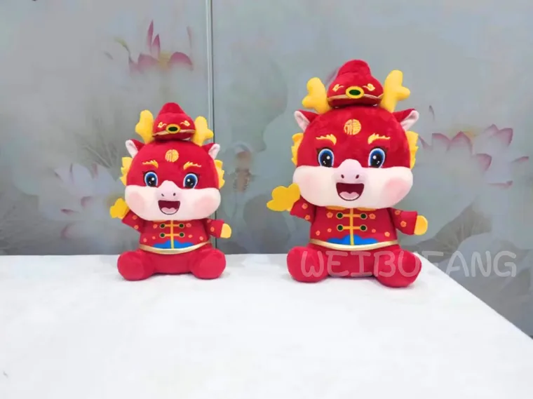 Two red festive dragons in coordinated embroidered outfits and different sizes.